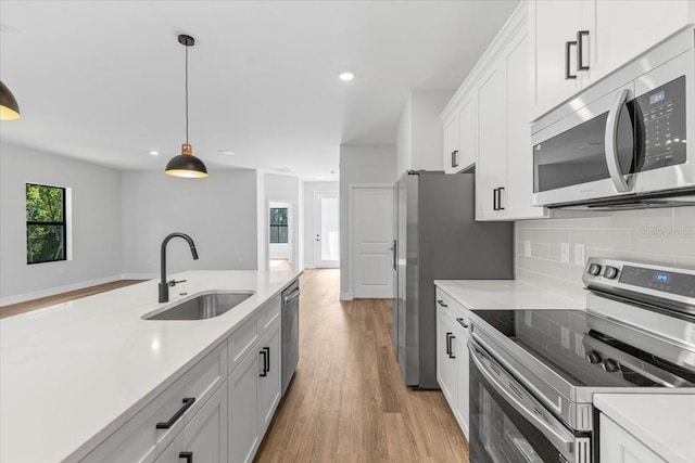 kitchen with tasteful backsplash, light countertops, light wood-style flooring, stainless steel appliances, and a sink