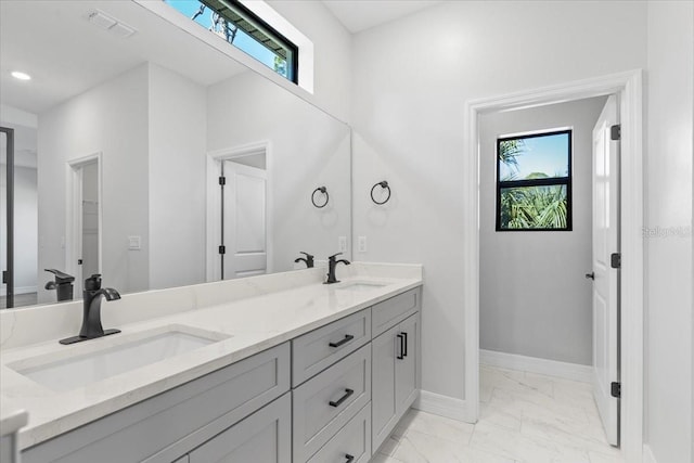 bathroom featuring plenty of natural light, marble finish floor, and a sink