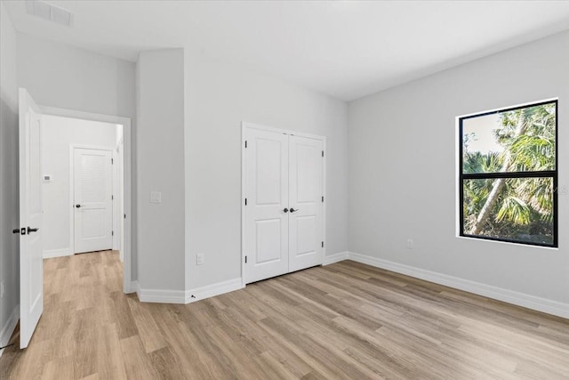 unfurnished bedroom with visible vents, baseboards, light wood-type flooring, and a closet