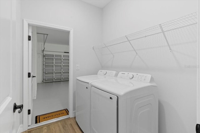 laundry area with laundry area, washer and dryer, and light wood-type flooring