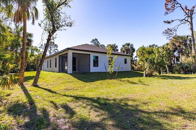 back of property featuring stucco siding and a yard