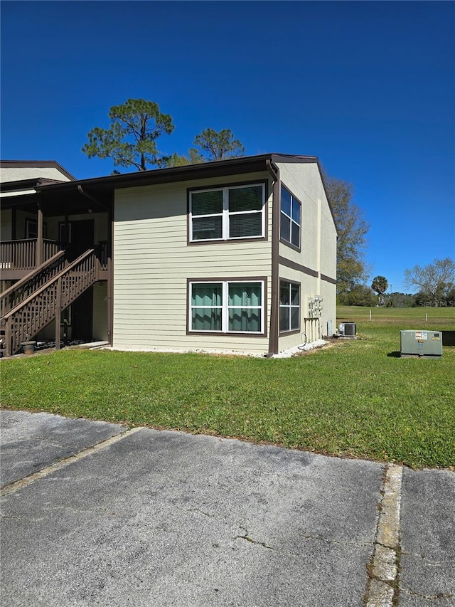 view of side of property featuring central AC unit and a yard