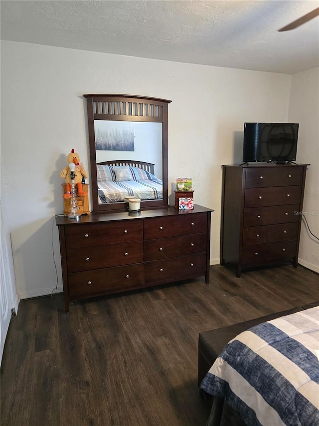 bedroom featuring baseboards, dark wood-type flooring, and a textured ceiling