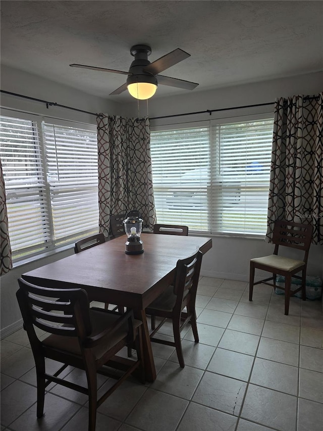 dining area with light tile patterned flooring, a textured ceiling, a ceiling fan, and baseboards