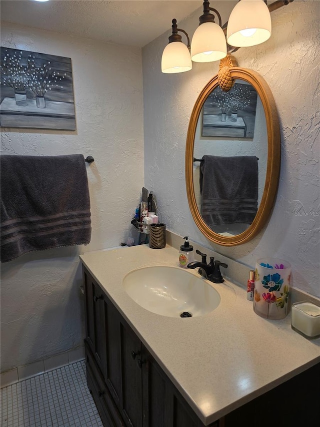 bathroom featuring tile patterned flooring, vanity, a textured wall, and a textured ceiling