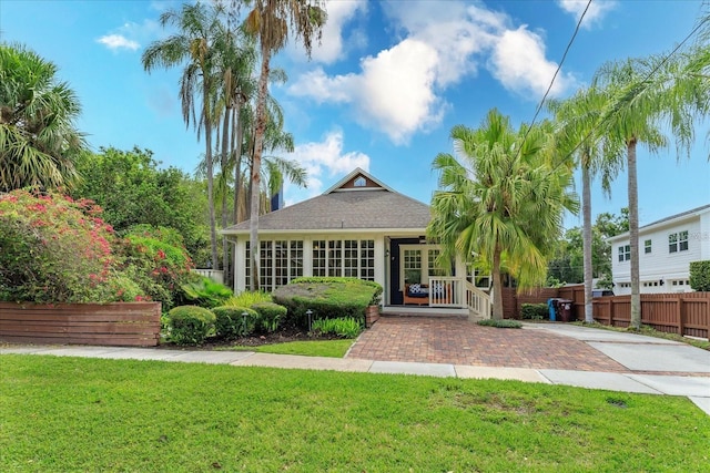 rear view of house with a lawn, covered porch, and fence