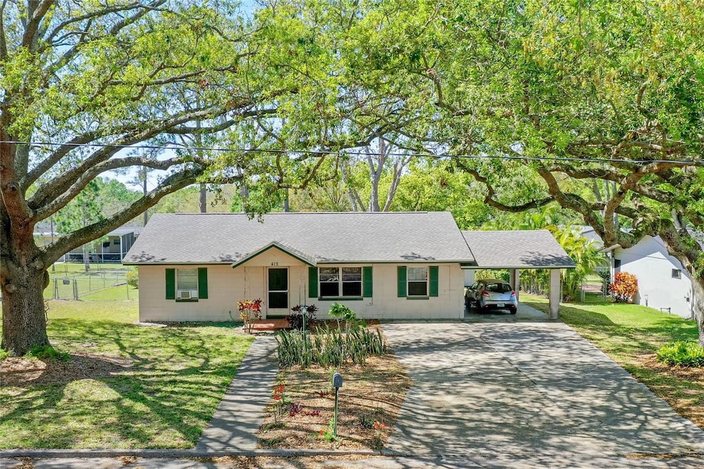 single story home with a carport, concrete driveway, fence, and a front yard