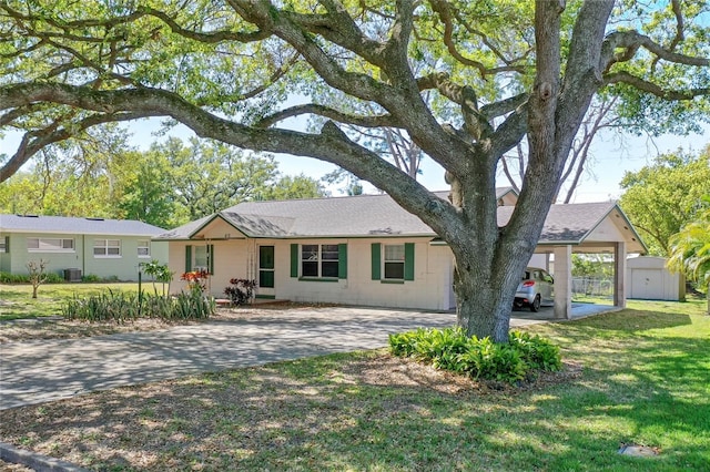 ranch-style home with a front lawn, a storage shed, an outdoor structure, a carport, and driveway