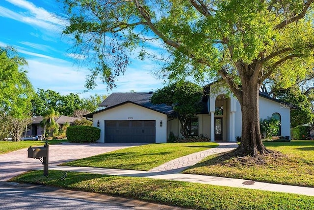 view of front of property with a front yard, a garage, driveway, and stucco siding