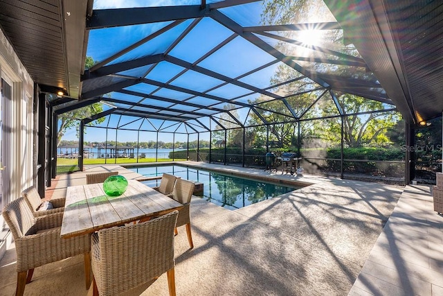 outdoor pool with glass enclosure, a patio, and a water view