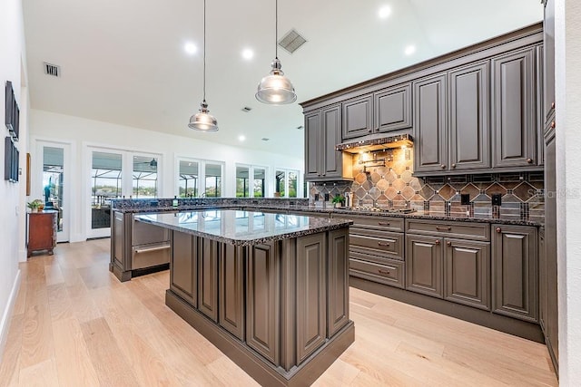 kitchen with dark stone countertops, visible vents, light wood-style floors, and a peninsula