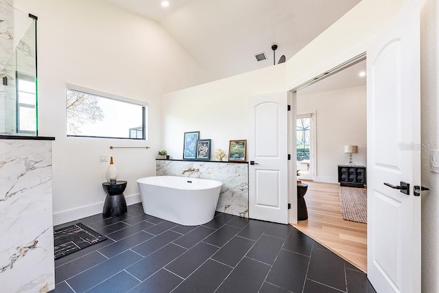 full bath with a freestanding tub, visible vents, lofted ceiling, wood finished floors, and baseboards