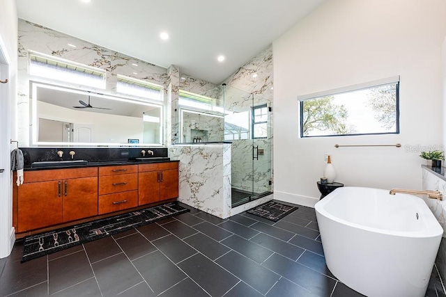 full bathroom featuring a marble finish shower, double vanity, lofted ceiling, a freestanding bath, and a sink