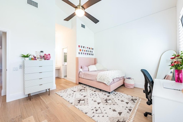 bedroom with baseboards, visible vents, light wood finished floors, and high vaulted ceiling