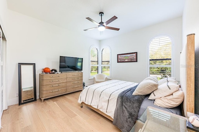 bedroom with light wood finished floors, ceiling fan, and baseboards