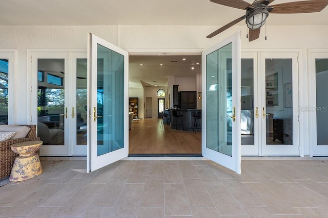 property entrance with a ceiling fan, a patio area, french doors, and stucco siding