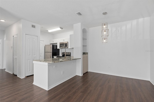 kitchen featuring light stone countertops, visible vents, stainless steel appliances, and a peninsula