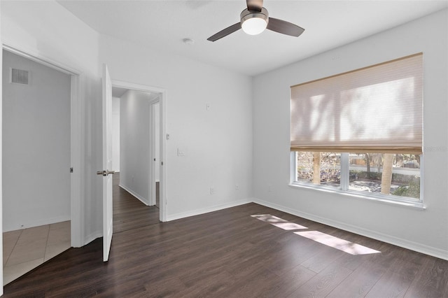empty room featuring dark wood-type flooring, baseboards, visible vents, and a ceiling fan