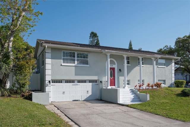 bi-level home with aphalt driveway, an attached garage, a front yard, and stucco siding