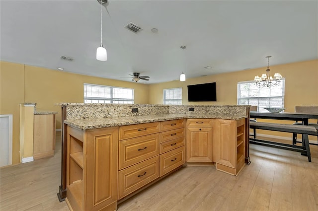 kitchen featuring open shelves, decorative light fixtures, light stone counters, and light wood finished floors