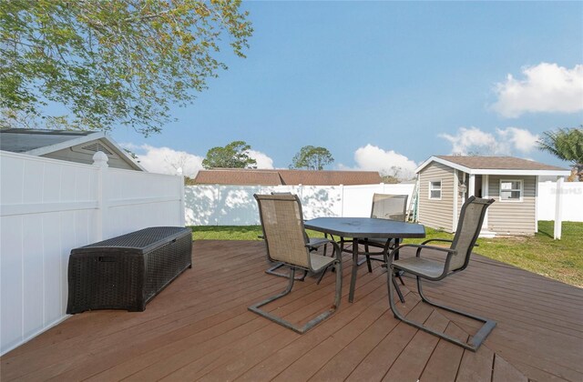 wooden deck featuring a fenced backyard, an outbuilding, and outdoor dining space