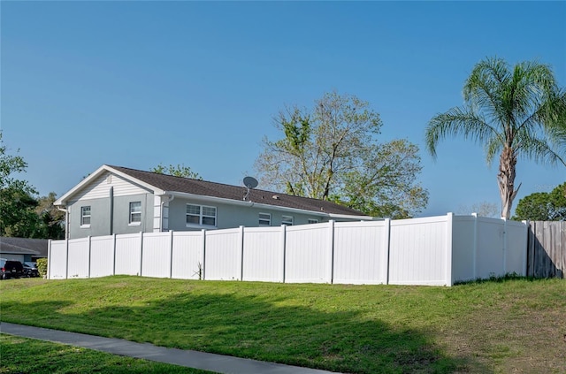 view of side of home with stucco siding, a lawn, and fence