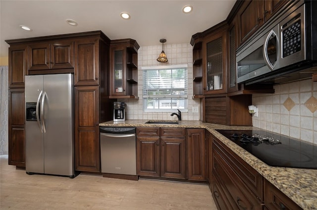 kitchen with light wood finished floors, dark brown cabinetry, light stone counters, stainless steel appliances, and a sink