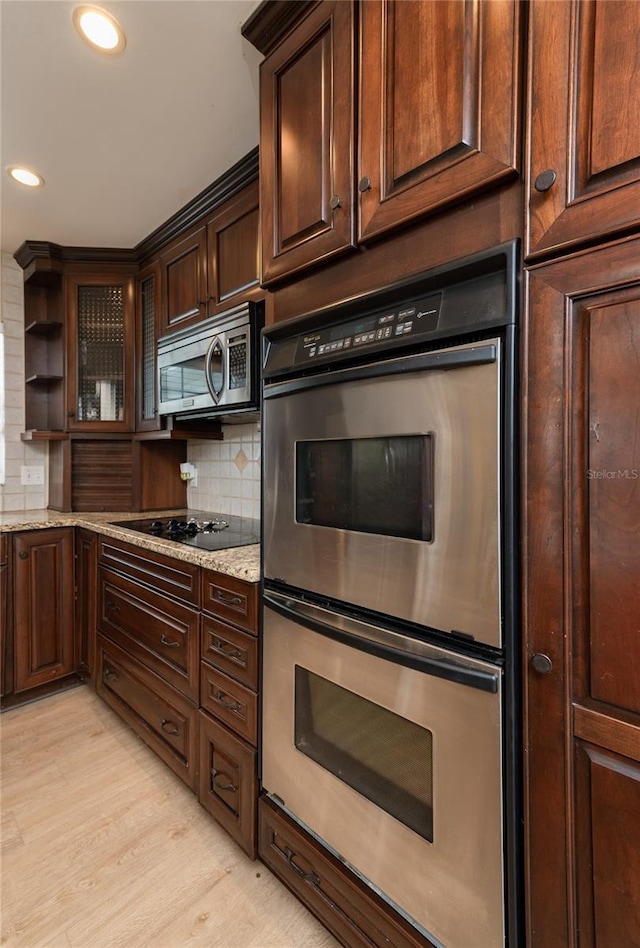 kitchen with open shelves, light wood-style flooring, dark brown cabinets, appliances with stainless steel finishes, and tasteful backsplash