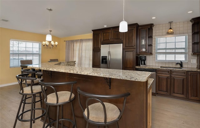 kitchen featuring decorative backsplash, light wood-type flooring, appliances with stainless steel finishes, and a sink