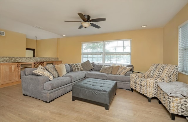 living room with a ceiling fan, light wood-style floors, and visible vents