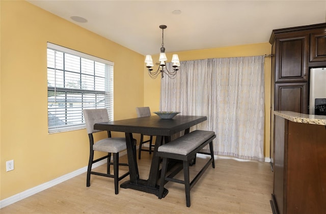 dining area with light wood-style flooring, a notable chandelier, and baseboards