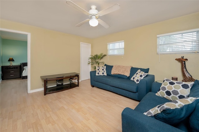 living area with baseboards, ceiling fan, and wood finished floors