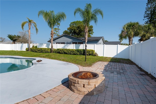 view of swimming pool featuring a fenced in pool, a fenced backyard, a fire pit, a patio area, and a lawn