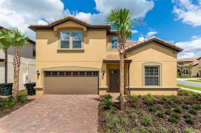 mediterranean / spanish house with stucco siding, decorative driveway, a garage, and a tile roof