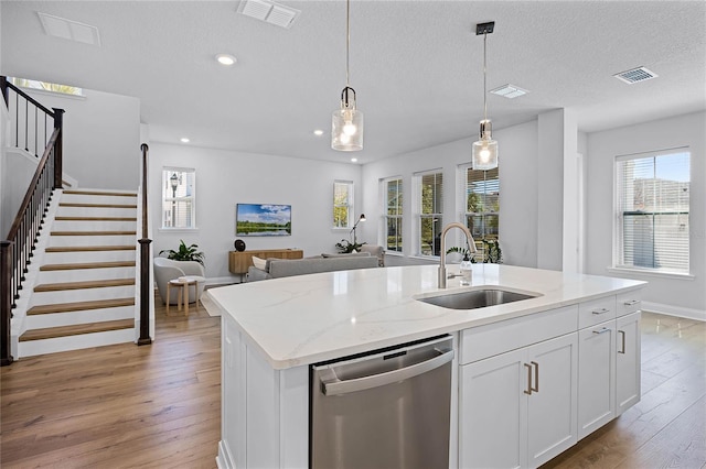 kitchen with visible vents, light wood finished floors, a sink, dishwasher, and open floor plan