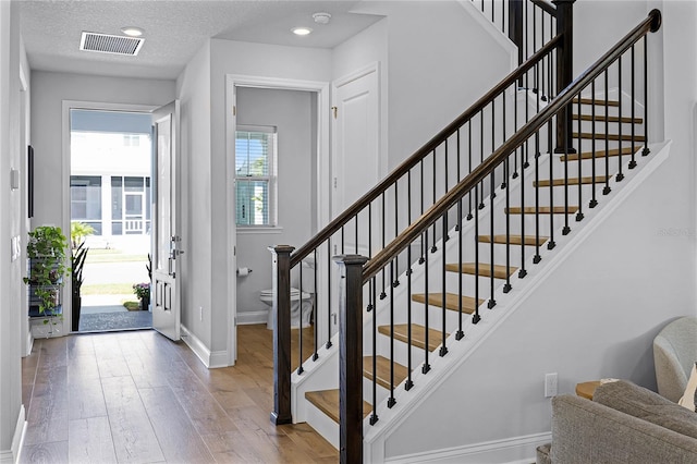 foyer entrance featuring visible vents, a textured ceiling, wood finished floors, recessed lighting, and baseboards