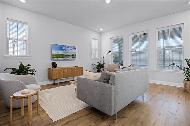 living area featuring recessed lighting, baseboards, and wood-type flooring