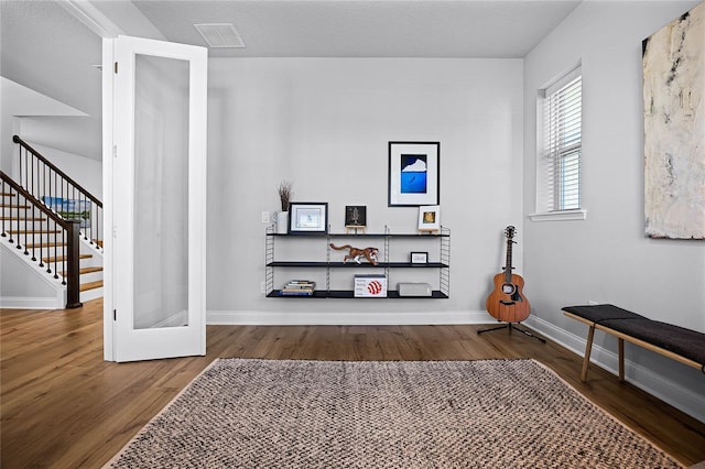 interior space featuring stairway, visible vents, baseboards, and wood finished floors