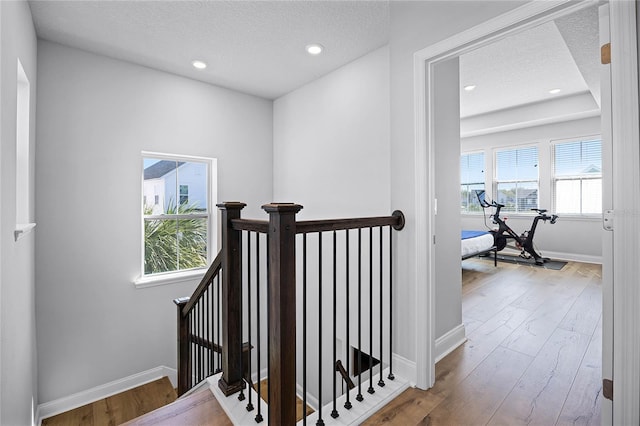 stairway with recessed lighting, baseboards, a textured ceiling, and wood finished floors