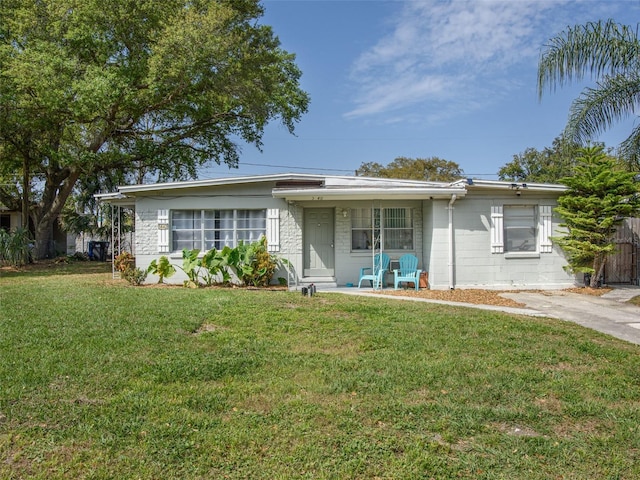 ranch-style home featuring a front lawn and concrete block siding