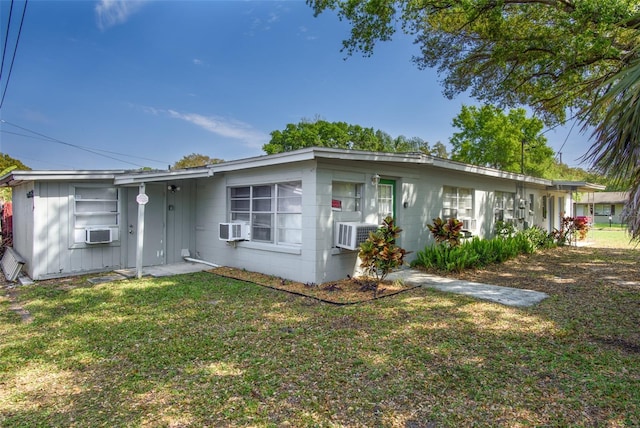 single story home with cooling unit, concrete block siding, and a front yard