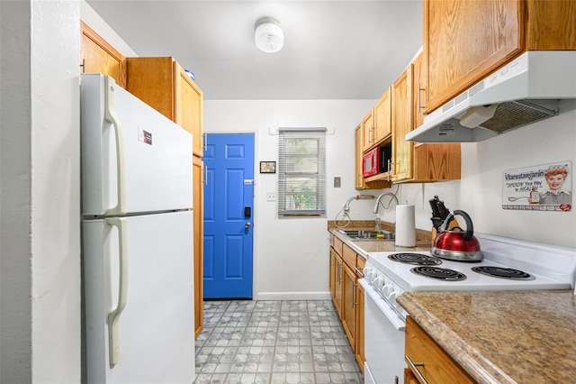 kitchen featuring baseboards, under cabinet range hood, light floors, white appliances, and a sink