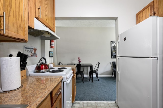 kitchen with light carpet, under cabinet range hood, white appliances, brown cabinetry, and baseboards