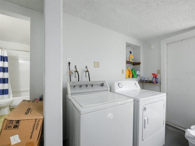 clothes washing area with laundry area, separate washer and dryer, and a textured ceiling