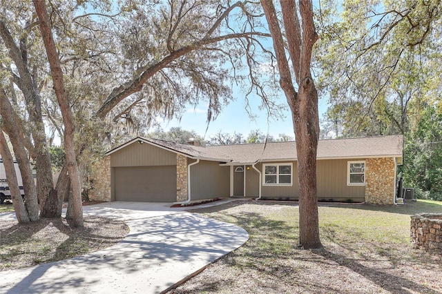 ranch-style home with stone siding, an attached garage, concrete driveway, and a front lawn