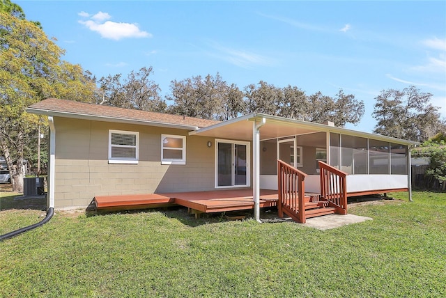 rear view of property featuring a lawn, a deck, cooling unit, a sunroom, and concrete block siding