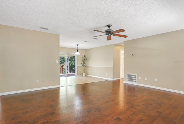 empty room with wood finished floors, visible vents, and ceiling fan