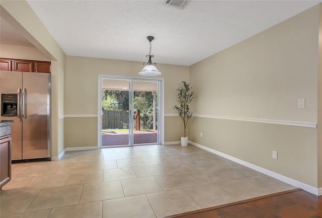 unfurnished dining area with light tile patterned floors, visible vents, a textured ceiling, and baseboards