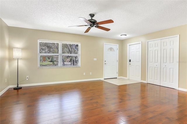 interior space with a textured ceiling, baseboards, a ceiling fan, and wood finished floors