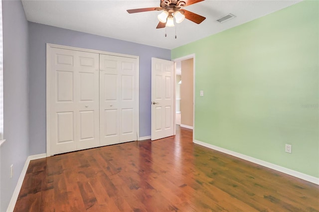 unfurnished bedroom featuring a closet, visible vents, baseboards, and wood finished floors